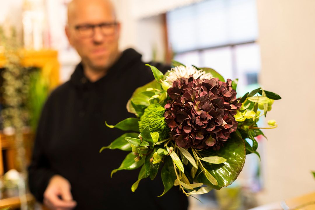 Florist Nicky Judel hält einen Blumenstrauß in die Kamera