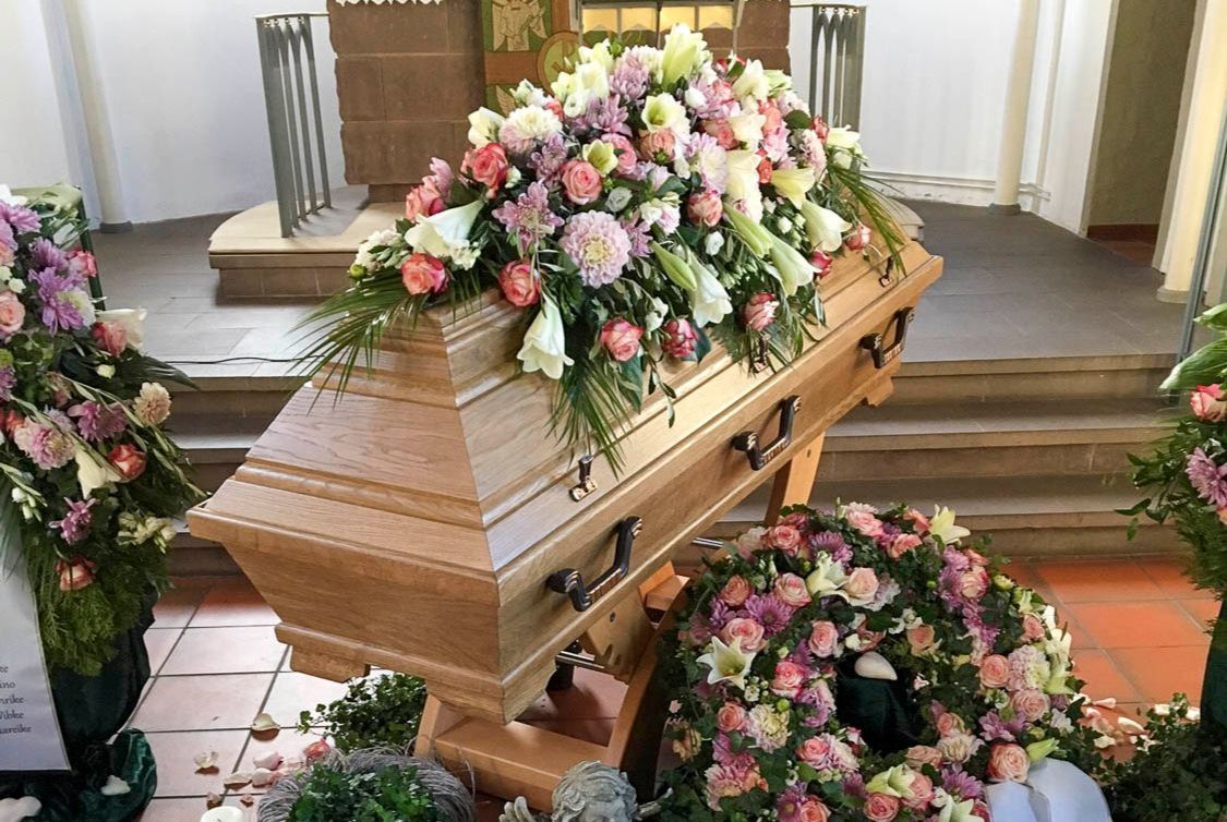Sarg mit Blumendekoration bei einer Trauerfeier